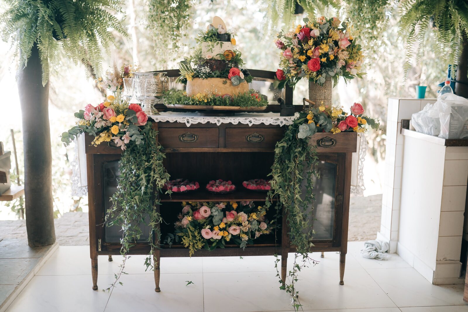 Mesa colonial de doces e bolo decorada com flores no Sítio Manacás