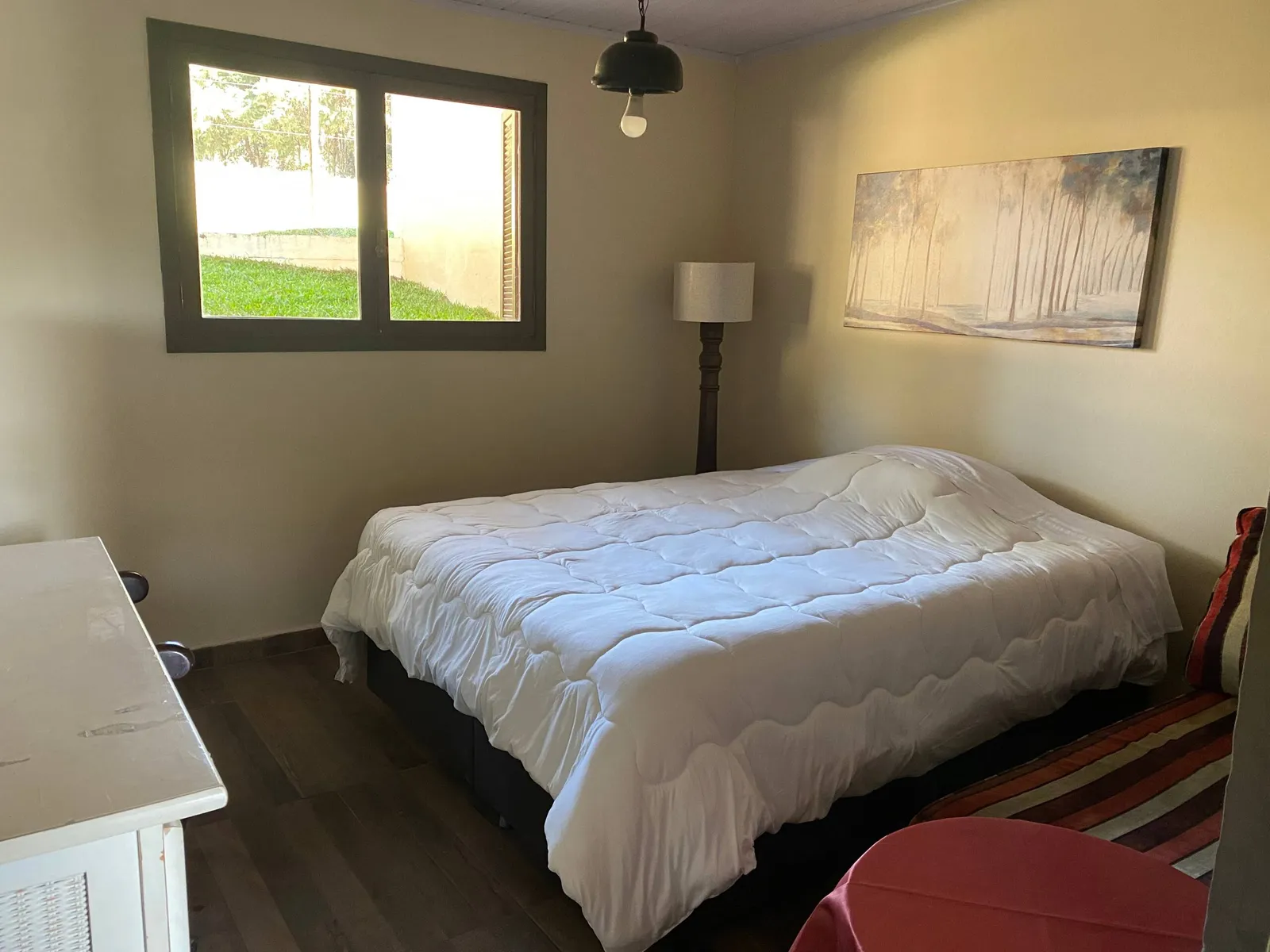 Quarto de hóspedes do Sítio Manacás com cama de casal e janela com vista para o gramado